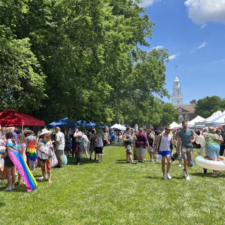 Crowds of people walking around festival lawn at Legislative Hall. Colorful festival tents sit along the lawn.
