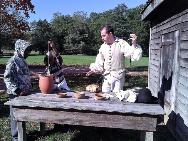 Photo of Historic-site interpreter Chris Merrill demonstrating how meat and fish are smoked.