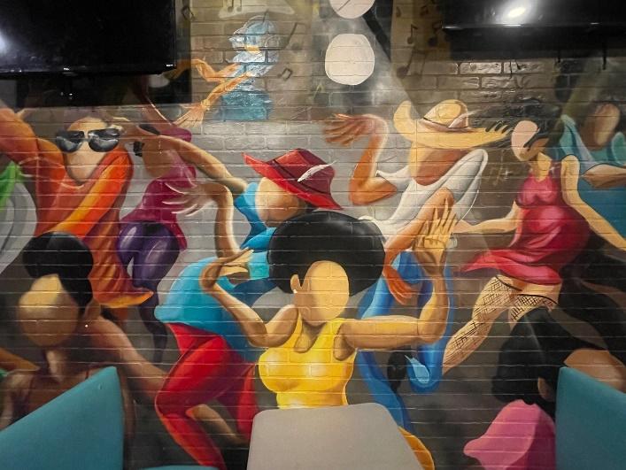 Image shows an example of colorful artwork, which is a modern remake of the popular "Sugar Shack" dancing scene by Ernie Barners, that can be found at Aunt Mary's.