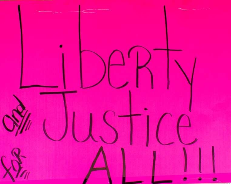 A hot pink sign reads "Liberty and Justice For All" and was donated in memory of Aliyah C. Simms.
