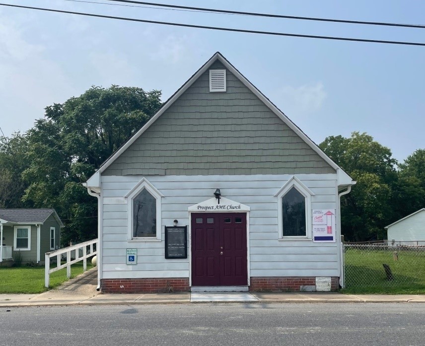 Image of Prospect A.M.E. Church, a small building with white siding, brick foundations, and a red door. 