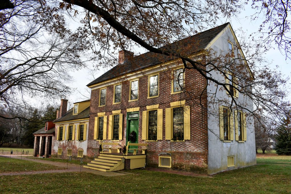 Photo of the John Dickinson Plantation Mansion - A red brick building with yellow windows and a green door