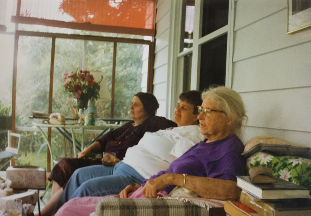 A photograph of three people gathered on a porch.