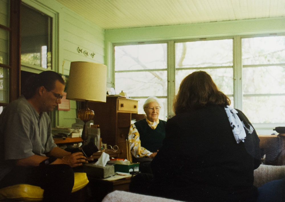 A photograph of three people gathered on a porch.