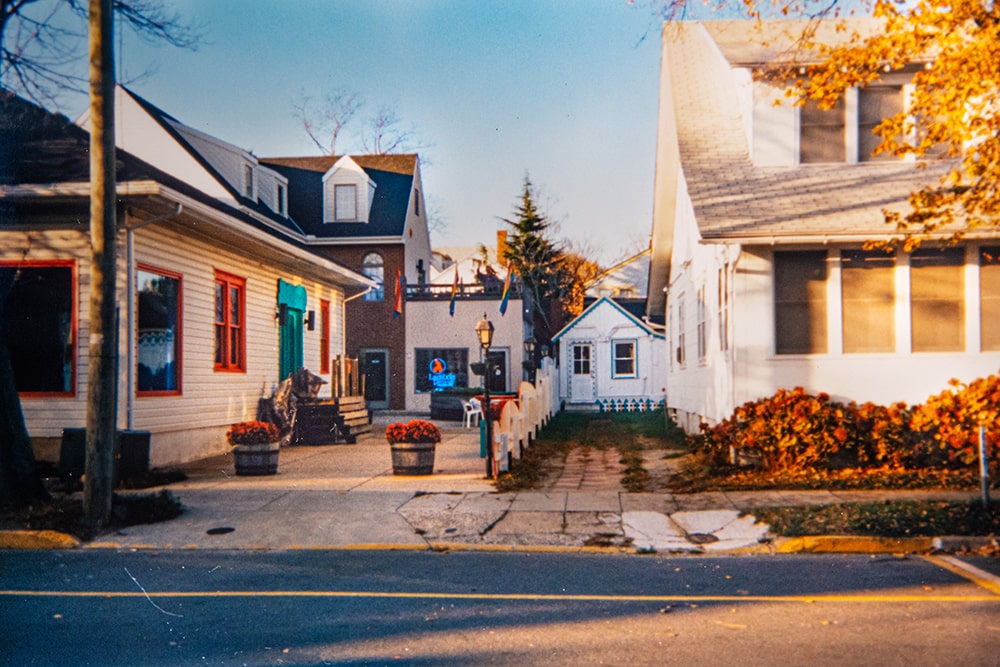 A street view of a commercial property on the left and a residential property on the right, divided by a fence.