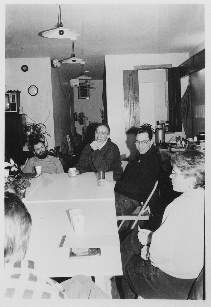 Five people sit around a table at a meeting.