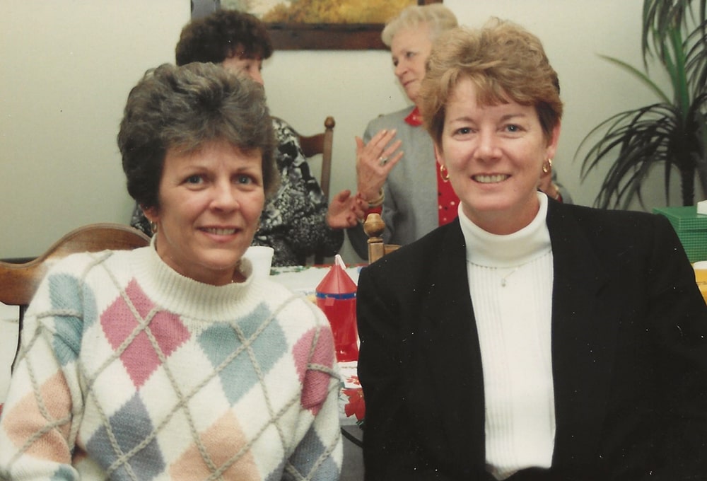 Two white women with short hair are pictured smiling at the camera.