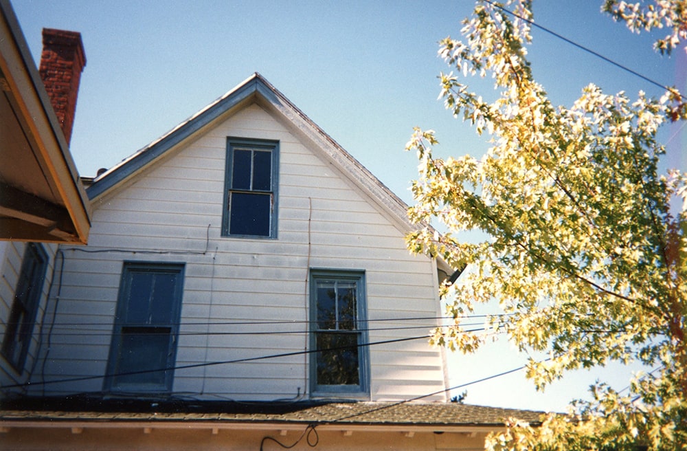 The roofline of a white house is seen half painted blue.