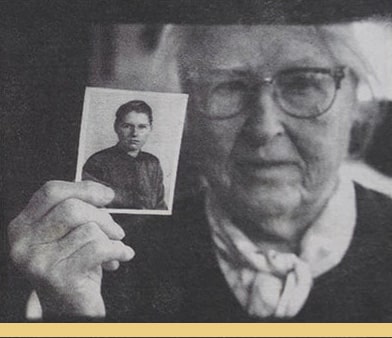 A photograph of an elderly white woman holding a photo of her younger self appears in a newspaper feature titled “Lesbian Gentility.”
