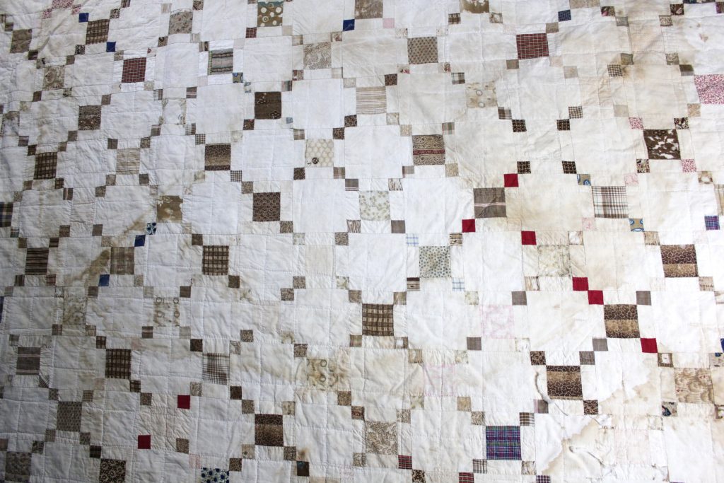 White quilt with various squares of different sizes and colors arranged in a check pattern