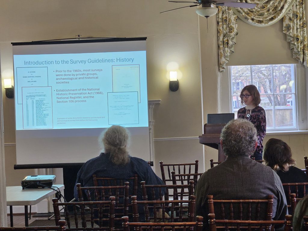 Hannah Lewis at the 2025 Delmarva Archaeology and History Symposium speak about an area project in front of several attendees.