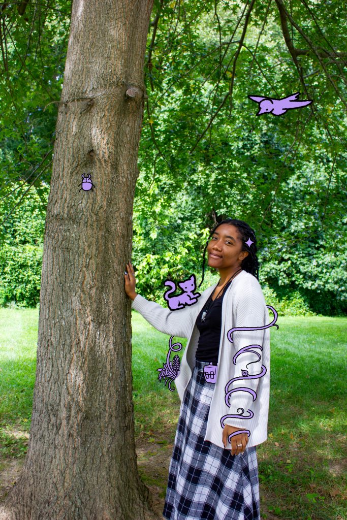 Person standing beside a tree, placing their hand on it as they smile at the viewer.