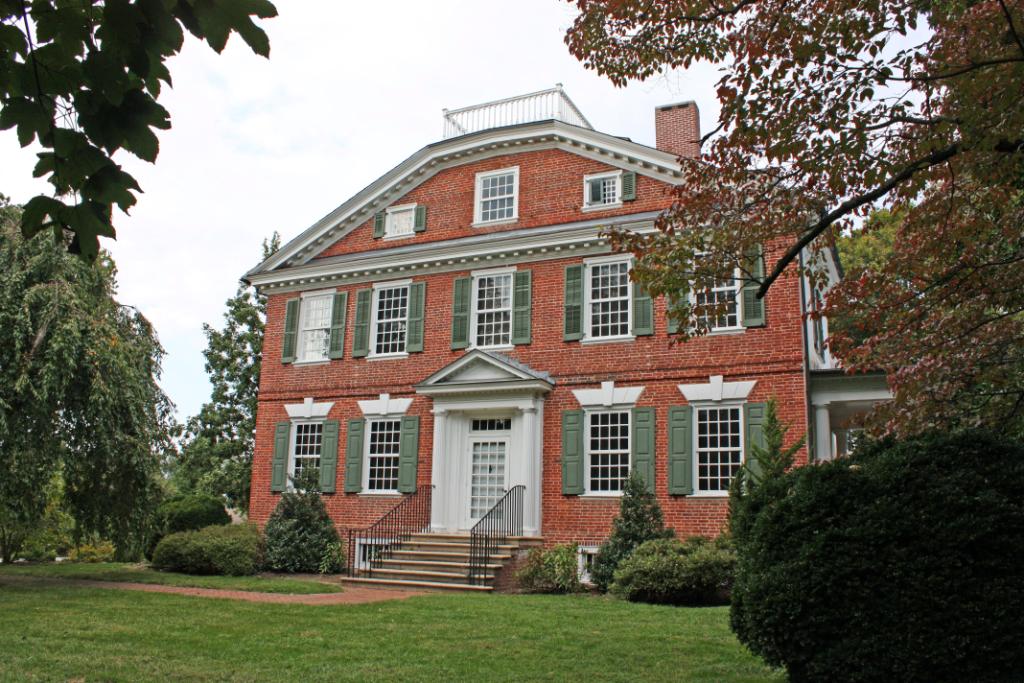 Belmont Hall, a Georgian house surrounded by threes and a cloudy sky