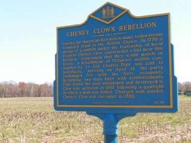 Deep blue and gold historical marker of Cheney Clow's Rebellion stands alone in a field