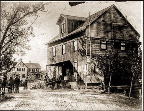 Older, black and white rendering of the Mill when there was an awning at the front entrance and trees to the right.