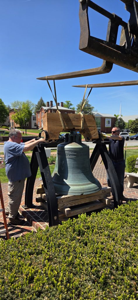 Bell yoke is lowered down with two workmen guiding the installation.