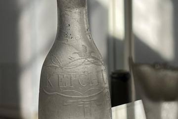 A clear glass ketchup bottle