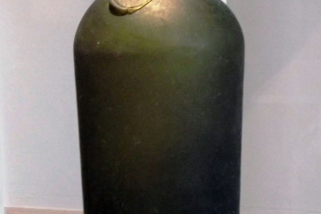 A dark green bottle with a short neck on display in the DeBraak exhibit